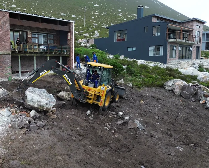 The TLB breaking granite hard against the existing house, split boulders lying where they came out