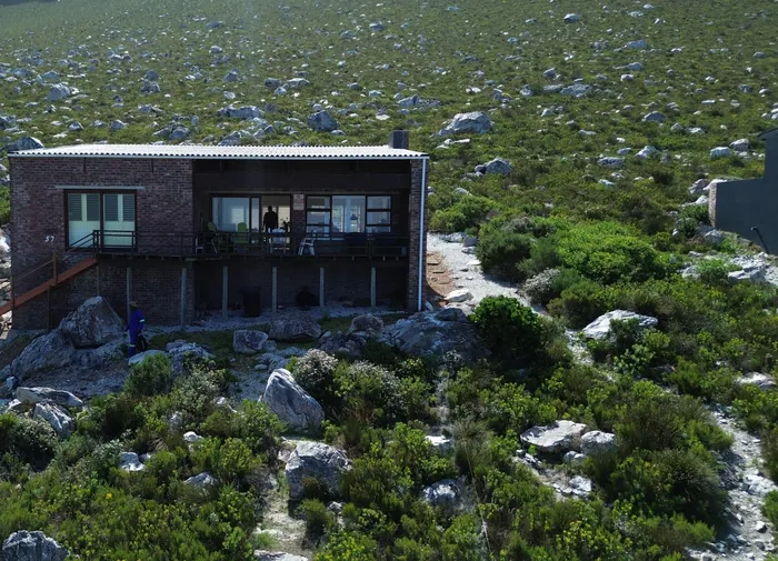 The existing home standing on its rock platform in the fynbos, the house the new level attaches to