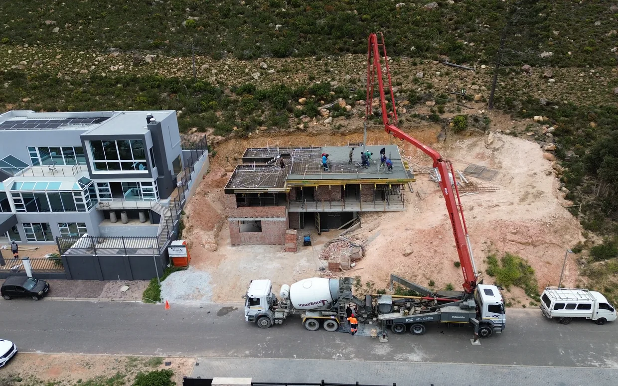 House van der Westhuizen: the pump reaching over the house to cast the second floor slab, with the crew working the concrete